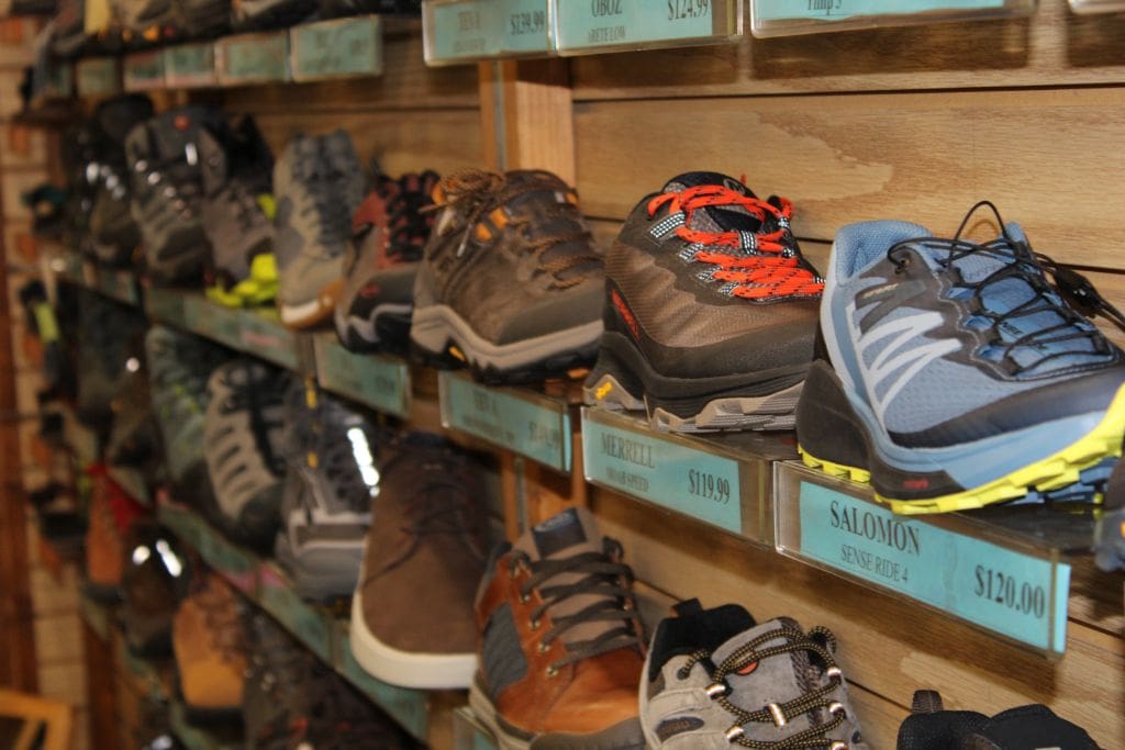 Assortment of hiking boots displayed on store shelves, with visible price tags.