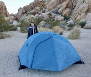 A woman standing by a blue tent