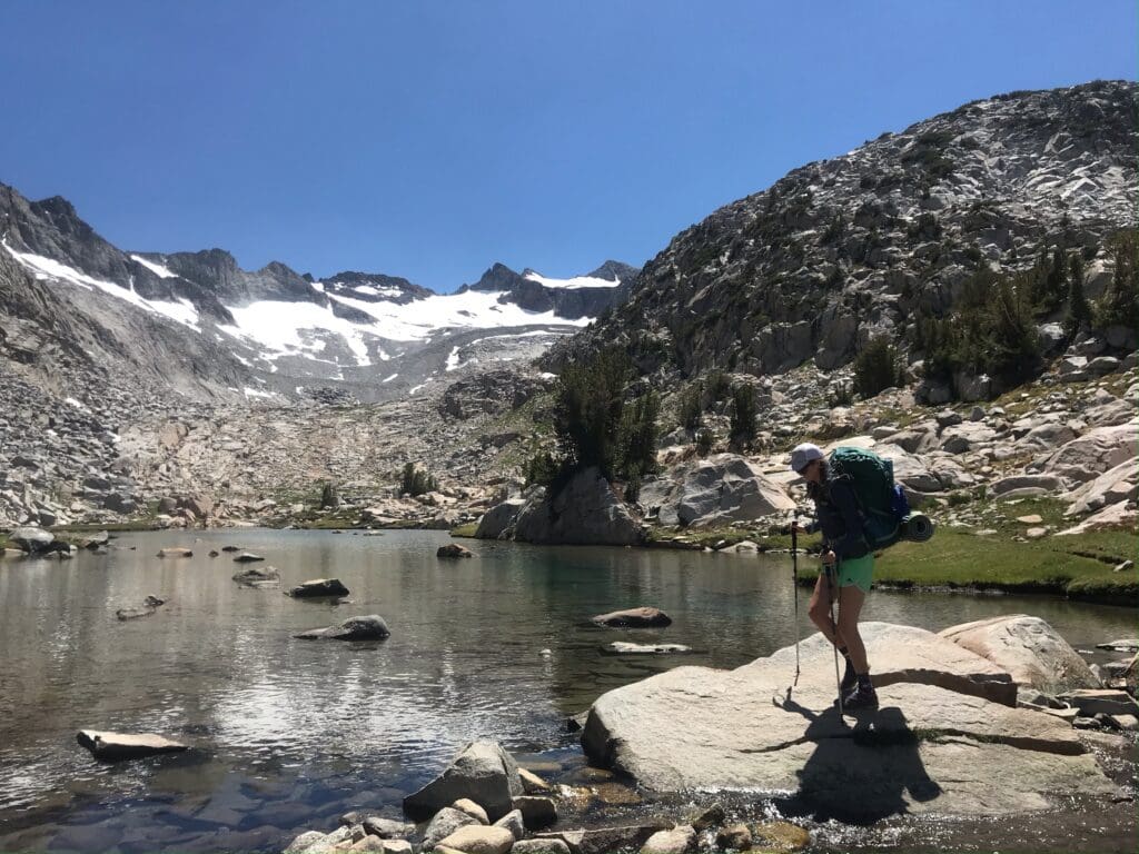 A person standing on a rocky path on a lake