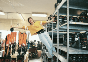 A woman is jumping in the air while holding onto some camera equipment.