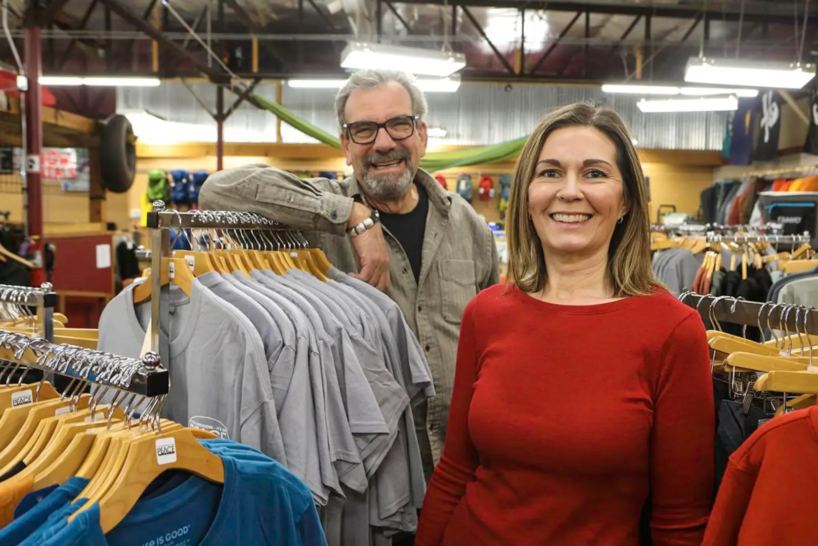 A man and woman standing in front of clothing.