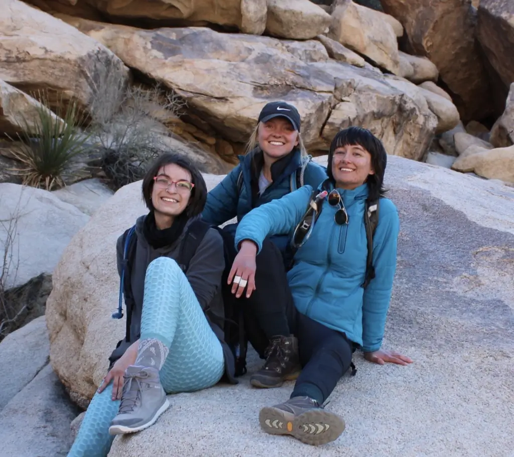 Three women sitting on a rock in the desert.