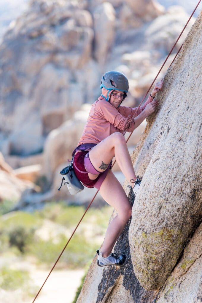 A woman climbing up the side of a rock wall.