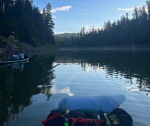 A person paddles on a lake surrounded by trees.