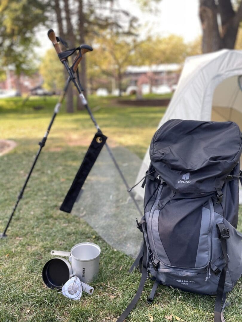 Black Deuter backpack, camping gear on grass.