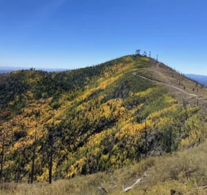 Mountaintop view with autumn foliage and antennas.