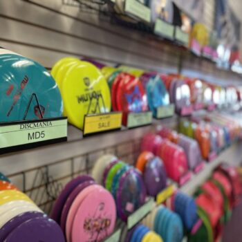 Colorful disc golf discs displayed on a retail store wall, with a focus on a blue disc labeled "discmania md5.